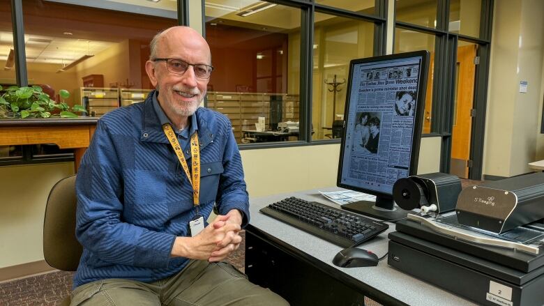 Librarian Mark Richardson sits at a desk with a microfilm reader.