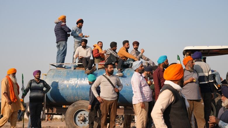 Farmers in India protest. Some are standing on top of a truck.