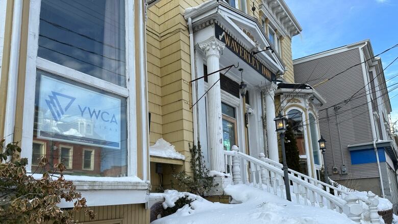 A yellow sided old hotel is shown with a YWCA sign in the window.