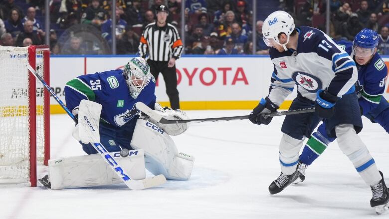 One hockey players shoots the puck past a goaltender.