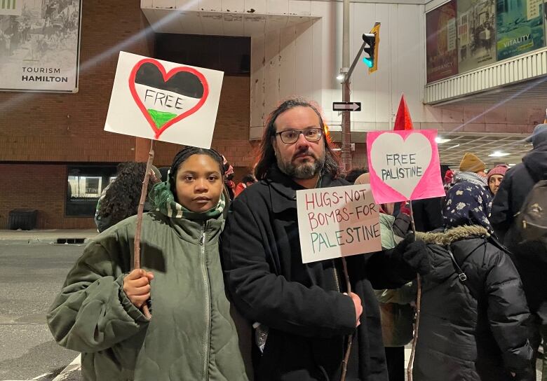 Two people standing and holding signs.