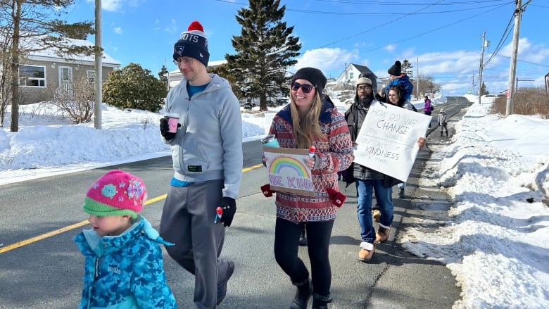 People walk along the road smiling holding signs