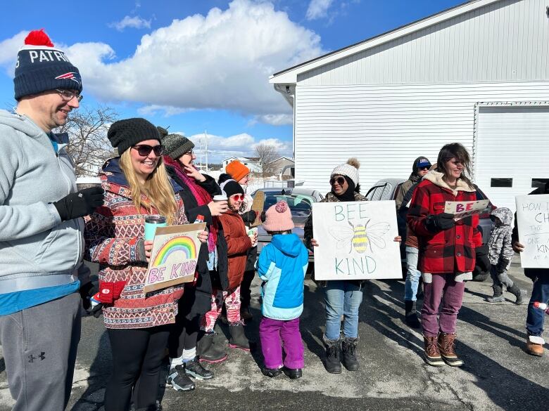 A group of people in winter clothes stand outside. 