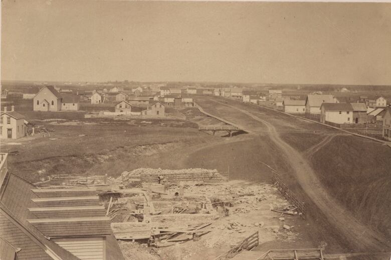 Sepia-toned image from the top of a building, looking out at mud streets and small wooden structures.