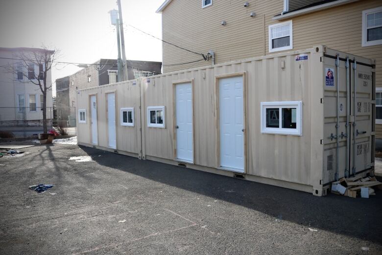 A beige shipping container sits in a snowy parking lot.