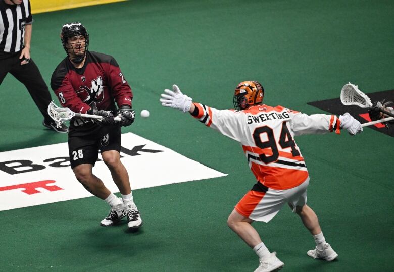 A lacrosse player stretches an arm out to try to block an opponent's shot.