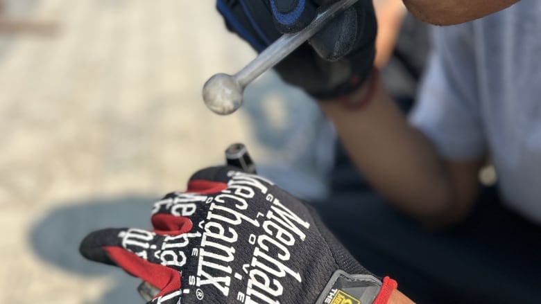 A hand wearing a biking glove holds a lighter to a drug pipe.