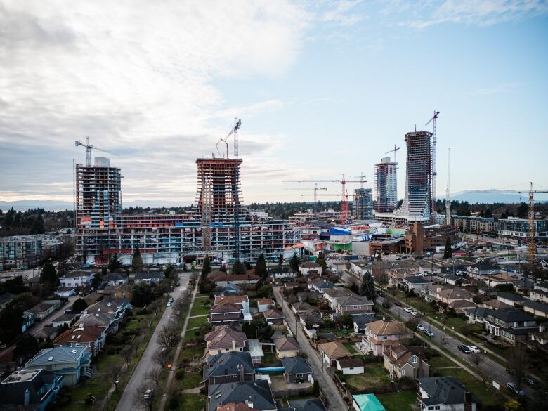 Under-construction towers surround single-family homes.