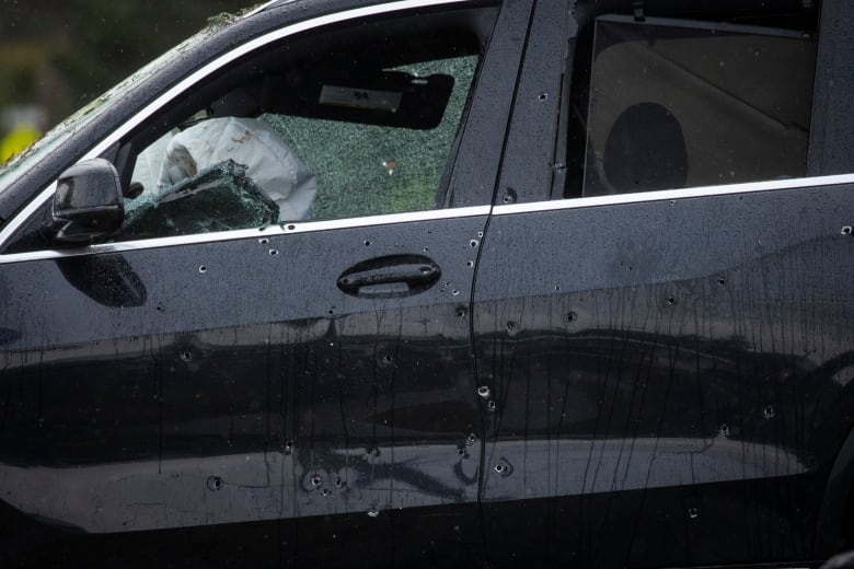 black vehicle riddled with bullet holes