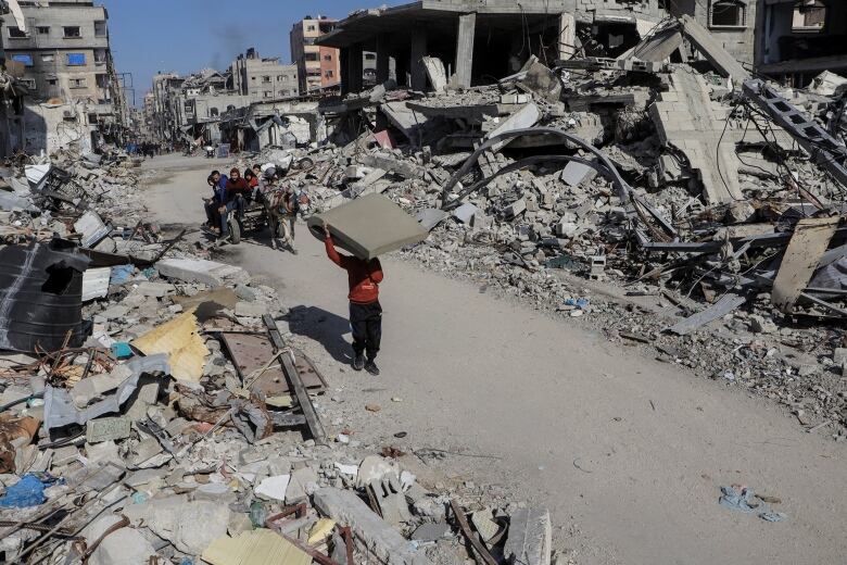 Palestinians walk past destroyed houses, amid the ongoing conflict between Israel and Hamas, in Jabalia refugee camp, in the northern Gaza Strip February 22, 2024. 