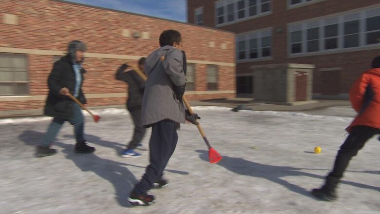 A group of people play broomball outside. 