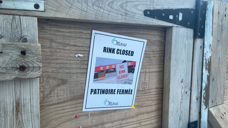 Sign on a wooden skating rink board doorway at Jack Purcell Park announcing that the risk is closed. 