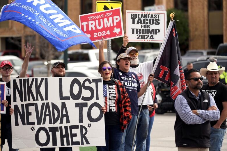 People on street hold signs with messages that say 