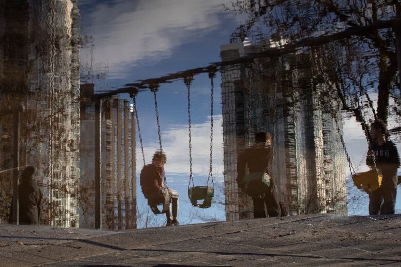 Children are reflected in a pool of water near Elsie Roy Elementary school in David Lam park in Vancouver, British Columbia on Tuesday February 7, 2023. 