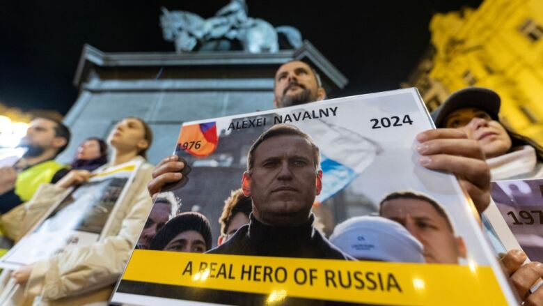 A man holds a placard in a public square.