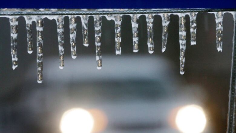 Ice hangs from a sign alongside an icy rural road Sunday, Jan. 18, 2015, near Newtown, Pa.