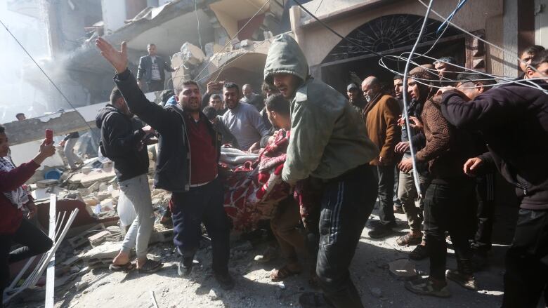 People carry an injured person amid rubble.