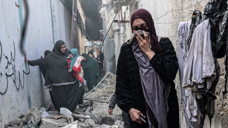 People navigate an alley covered in rubble.