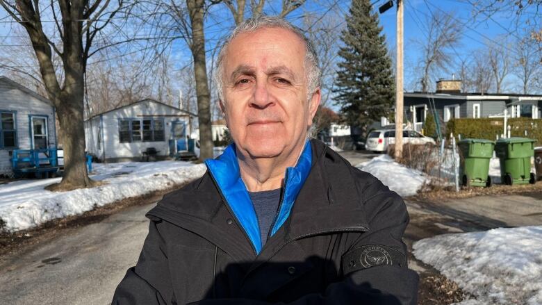 older man in winter coat standing outside in a suburb