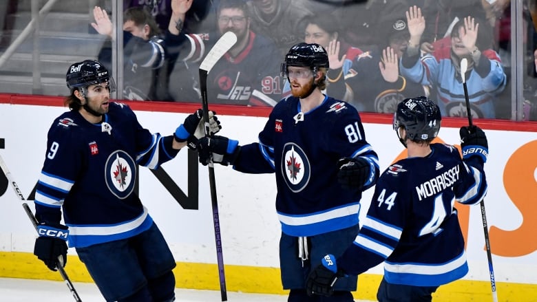 Hockey players in dark blue uniforms group together in celebration