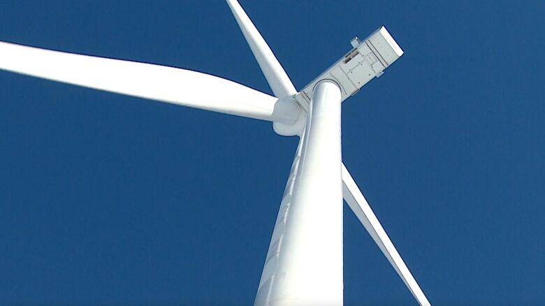 A wind turbine is pictured with a clear blue sky in the background.