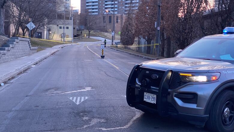 A police car in front of police tape on a street.