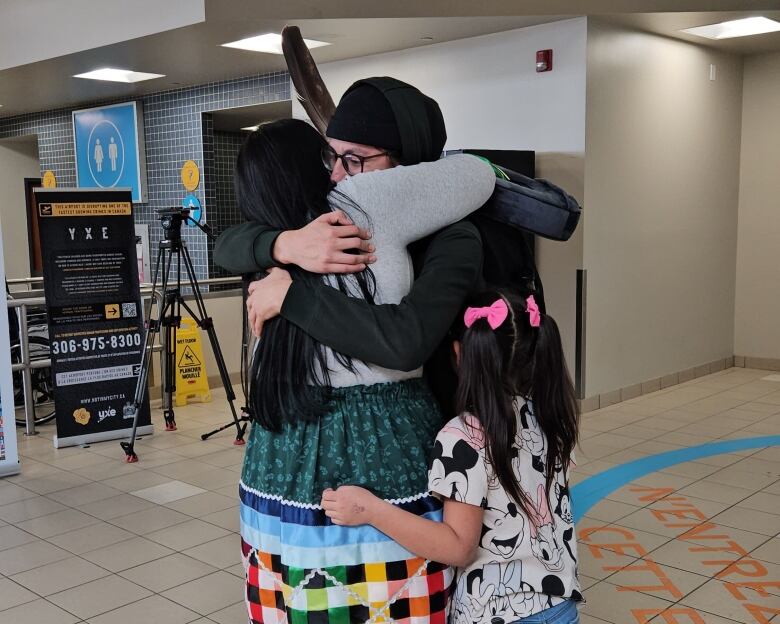 A family are hugging in the airport after being apart for some time. 