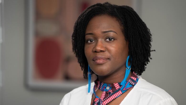 A female family physician wearing a striped tie and blue earrings. 