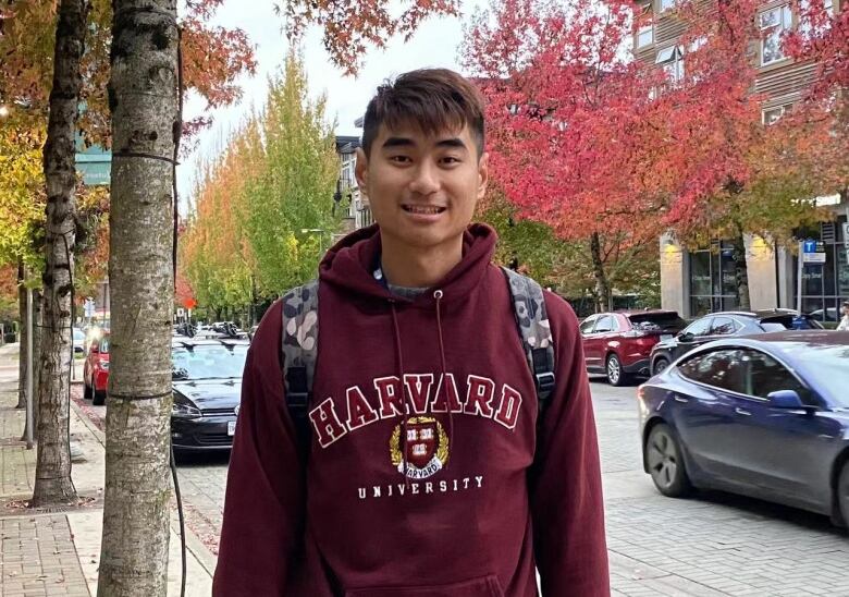 A man stands on the grounds of UBC smiling at the camera.