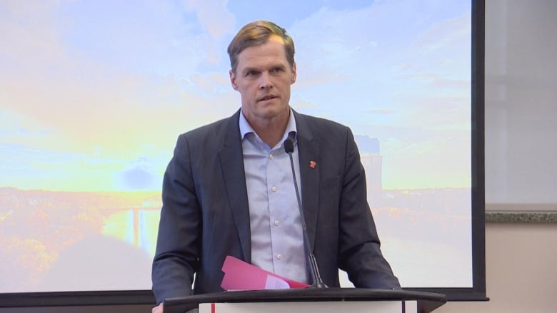 A man stands behind a podium speaking into a microphone. 