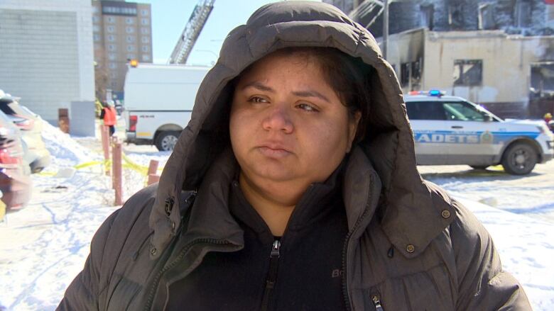 A woman speaks to a reporter while wearing a hooded parka. 