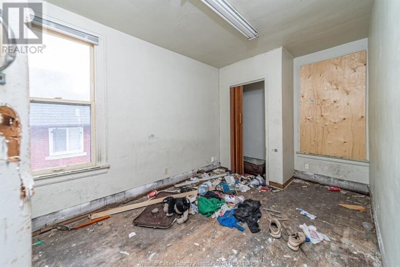 A bedroom in need of repair, with garbage strewn on the floor.