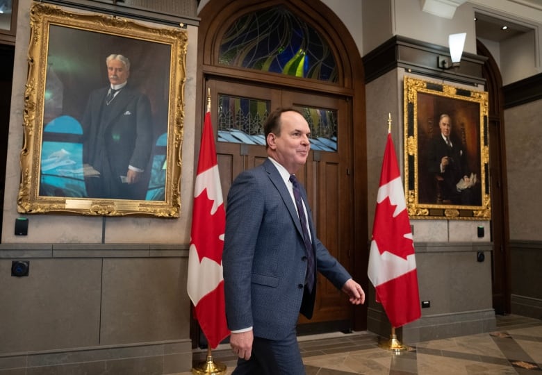 A politician walks toward a news conference in a legislature lobby.