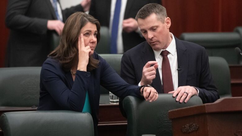 a woman and man talk while sitting at parliamentary benches