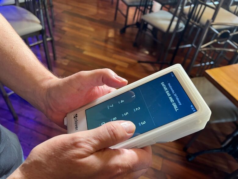 A clover payment device is held at a restaurant.