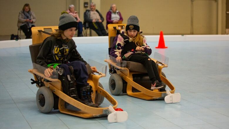 Two kids drive a motorized wheelchair for sports.