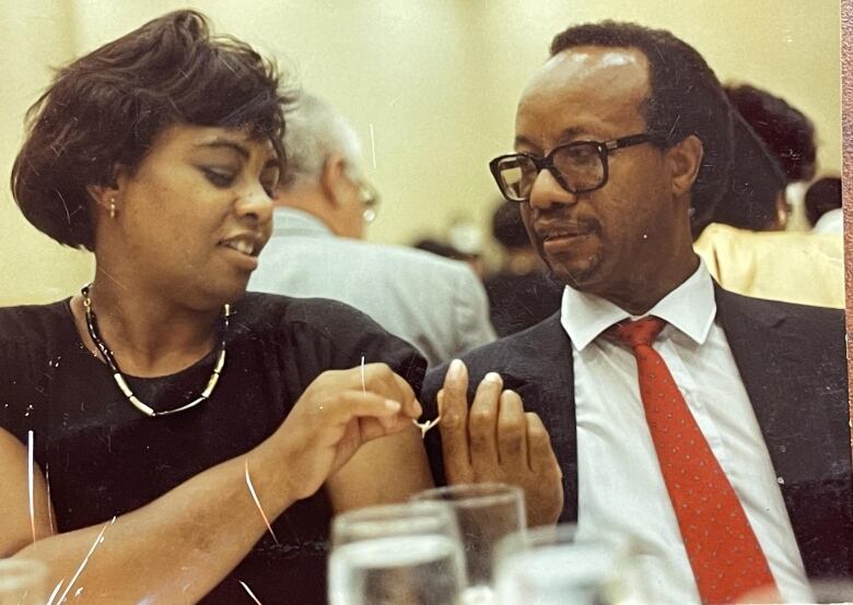 A Black women and man prepare to split a wishbone at a group dinner.