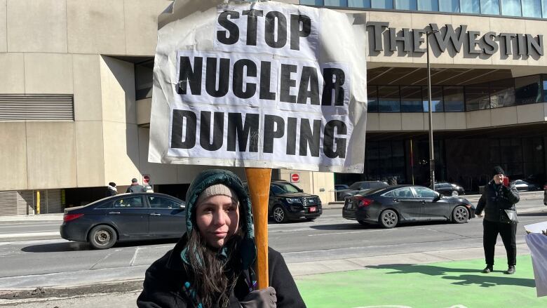 A woman holds a sign that says, 