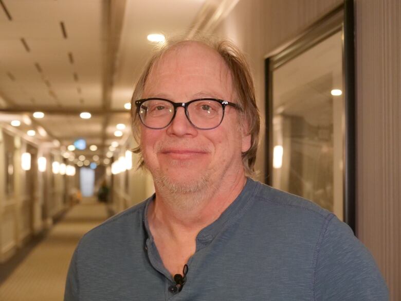 A portrait of a smiling man in a hallway.