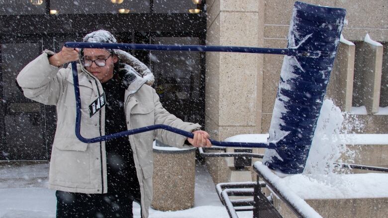 A person shovels snow outside a building.