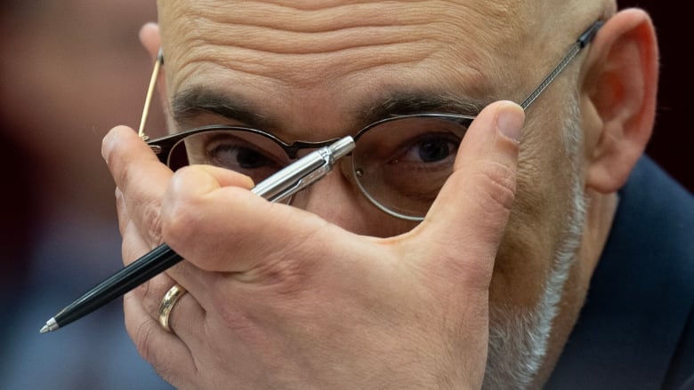 Parliamentary Budget Officer Yves Giroux adjusts his glasses as he waits to appear before the Senate Committee on National Finance, Tuesday, October 17, 2023 in Ottawa. Giroux is projecting inflation will return to the Bank of Canada's two per cent target by the end of the year and the federal deficit will grow amid weakening economic conditions.