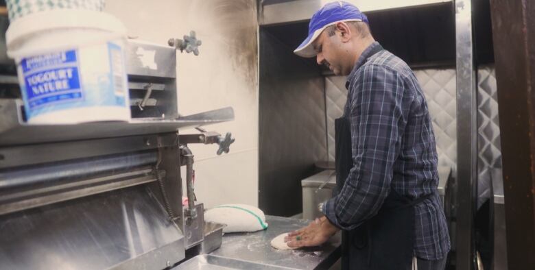 A cook makes naan bread in the kitchen of Al-Buraq restaurant.