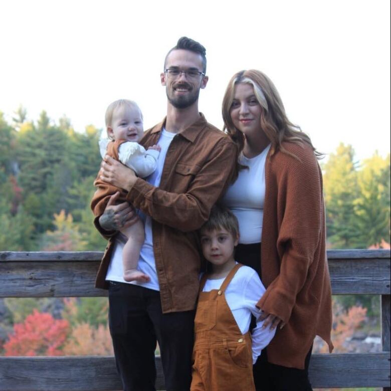 A family posing with fall colours in the background.