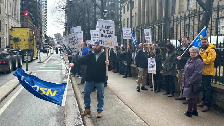 A group of correctional officers stand with NSGEU flags and sign that say 