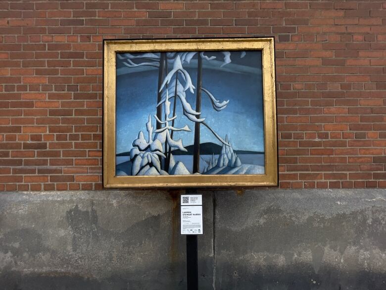 A group of seven painting highlighting snows sits framed against a brick wall.