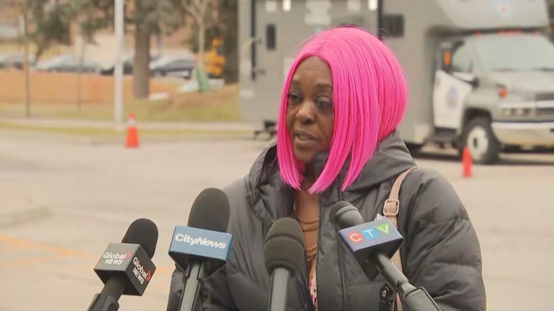 A woman speaks in front several microphones.