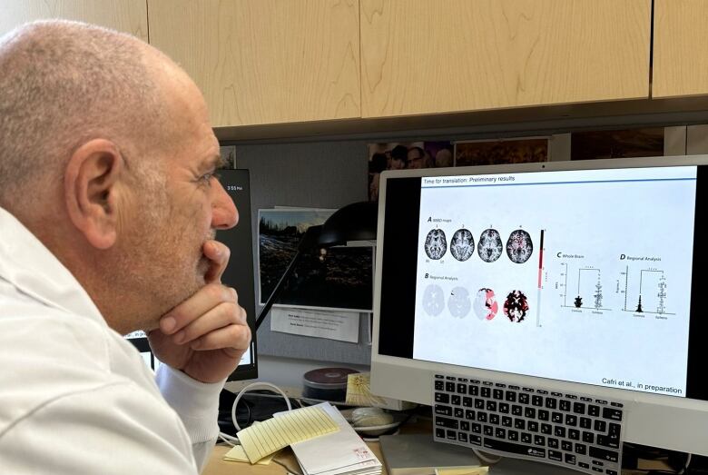 A man with short grey hair looks at a computer screen.