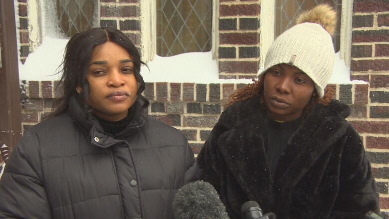 Two women wearing winter jackets are pictured standing side-by-side.