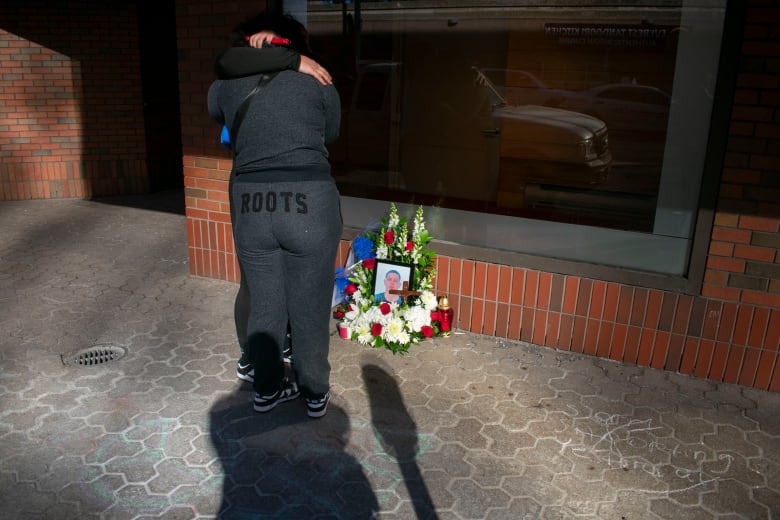 Two people hugging next to a picture on the ground.