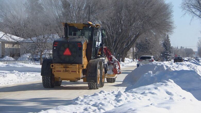 a big yellow machine driving down the road behind other vehicles